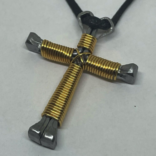 A small gold cross of nails necklace on a black cord.
