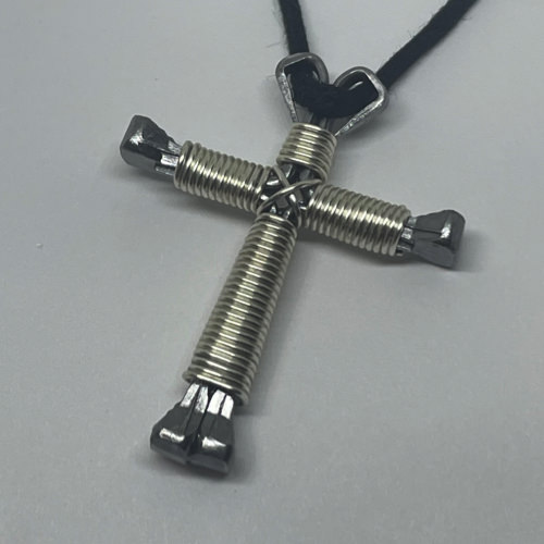 A small shiny cross of nails necklace on a black cord.