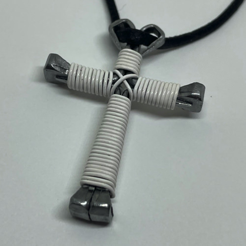 A small white cross of nails necklace on a black cord.