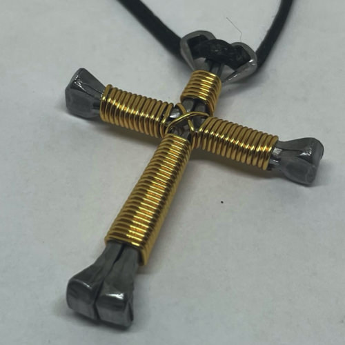 A horseshoe nail cross necklace wrapped with thin gold wire