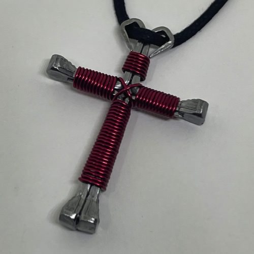  magenta horseshoe nail cross necklace on a black cord.
