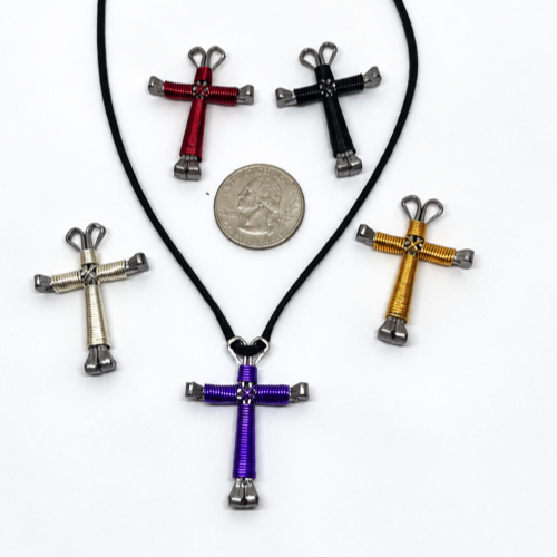 Five small horseshoe nail crosses in different wire colors beside a quarter